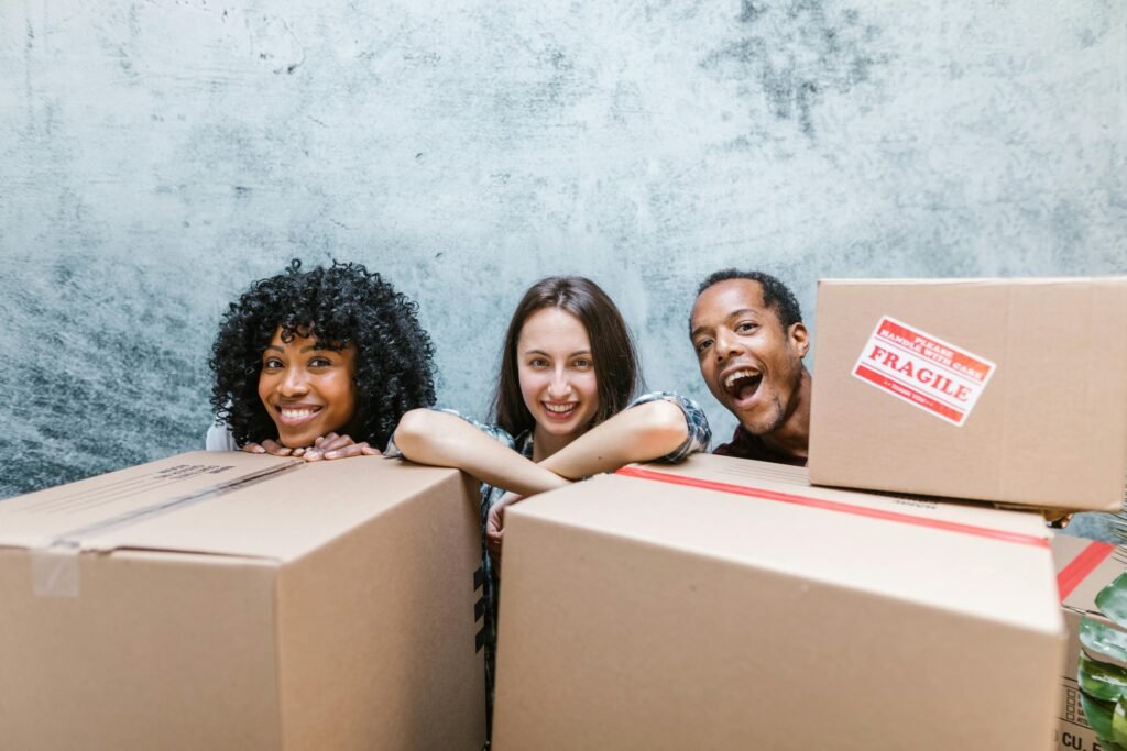 Three friends happily unpacking moving boxes during their move-in day.